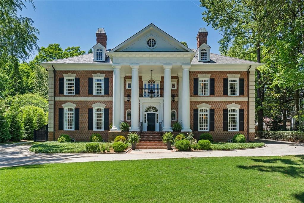 This statuesque Neoclassical brick estate, situated on over an acre of lush grounds in the heart of Druid Hills, is simply extraordinary. Stately porch leads you to an expansive, inviting foyer featuring classic dentil moulding, beautiful light, and 10-foot ceilings. Interior is fully renovated and brilliantly reimagined, presenting a sunlit living room and family room, large dining area with marble fireplace, and designer-sourced Circa light fixtures. Kitchen features slab marble backsplash, hidden walk-in pantry, gorgeous inset custom cabinetry, and incredible island spanning nearly the entire length of the kitchen. Primary bedroom features a vaulted shiplap ceiling, oversized closet with discreet custom storage, and spectacular primary bath with elegant marble finishes. Spare bedrooms include harmonious ensuites, walk-in closets, and generous light. Separate dedicated guest suite with bedroom, living area, kitchenette, and full bath with equally high-end finishes. Massive third story space is ideal for play area or office and stubbed for plumbing for an extra bath. The terrace level is a delight, featuring an enormous media room, large gym, stylish full bath, spare bedroom, and ample storage. 3 car garage; large mudroom with back stairs to the second level. The pièce de résistance is the incredibly lush, serene, quintessential Druid Hills lot spanning over an acre, and visible from multiple vantage points on the main and upper levels of this exquisite home. Gorgeous outdoor living space, ideal for lounging and entertaining. This iconic home is a joy to behold. Welcome home!