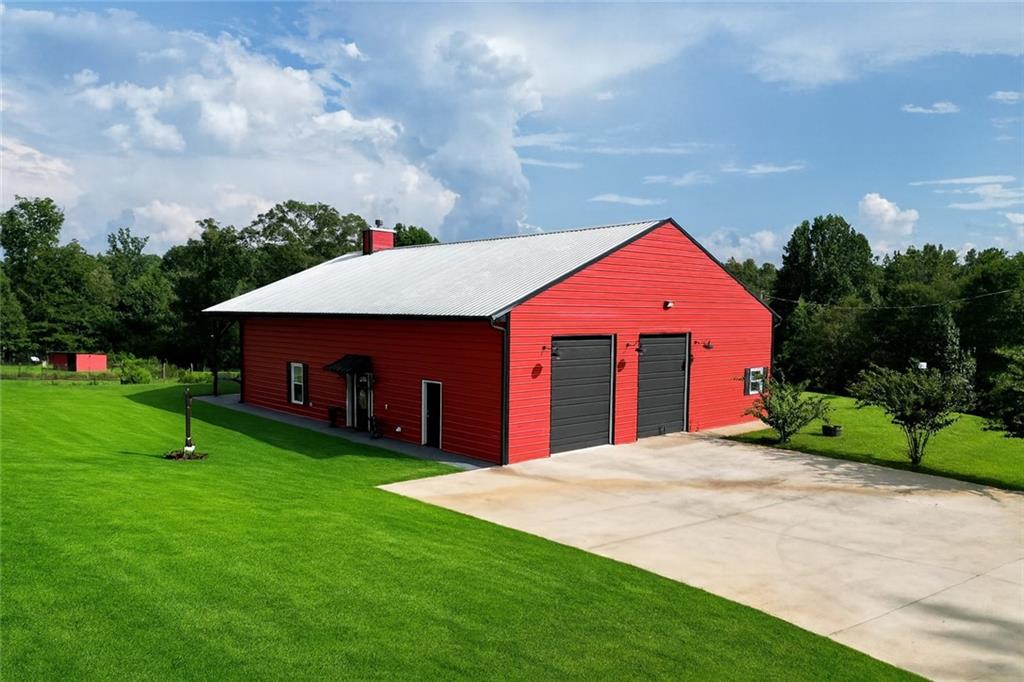 Nestled on 5.01 private acres, this beautiful Barndominium retreat offers an unparalleled blend of luxury and country charm. Located just 20 minutes from downtown Athens and the University of Georgia, and 20 minutes from Commerce, this property offers privacy, exceptional craftsmanship, and endless possibilities.
The heart of this home is the spacious open-concept living area, featuring vaulted ceilings with exposed wooden beams, a wood-burning fireplace (with gas hookup) with cedar accents, and a stunning kitchen with a large granite island, farmhouse sink, floating shelves, and soft-close cabinetry. The main-level master suite is your own private retreat, with a luxurious bathroom featuring double vanities, a soaking tub, and a custom tile shower. Two additional bedrooms and a full bath are located on the opposite side of the home, providing privacy for family or guests.
Step outside and take in the beauty of your 5 acres from the covered back patio, complete with two ceiling fans and gas & water lines ready for your future outdoor kitchen. The property also features a chicken coop, goat barn, storage shed, shooting range and scenic trails to explore. An acre+ of the land is fully fenced with three gates, including a solar-powered entrance gate—ideal for pets, livestock, or creating your own private sanctuary.
The real showstopper? Besides the amazing sunsets, is the massive garage space! Currently serving as a gym, arcade, bar, and flex space, this unique area offers endless potential. Whether you're looking to run a business, store equipment, or create your own dream setup, this versatile space has you covered. It’s perfect for entrepreneurs, hobbyists, or anyone seeking room for expansion.
Conveniently located with easy access to schools, shopping, and major roads, but still private with lots of potential.
If you're looking for the perfect balance of luxury, country living, and proximity to everything you need, this one-of-a-kind barndo is a must-see. Schedule your private tour today!