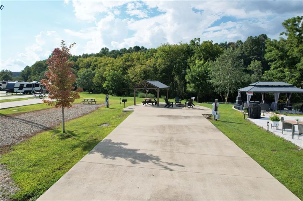Creekside retreat - settle into the sounds of Hemptown Creek with this premium RV lot designed for relaxation and entertaining. The property features a long concrete pad to easily fit larger RVs, along with a pavilion already wired with power, making it a great spot for outdoor dining, game days, or evenings under the lights.
A custom in-ground fire pit surrounded by high-quality Adirondack chairs invites you to unwind by the flames while listening to the creek just steps away. The pavilion with top-tier picnic table creates another comfortable gathering space, which is perfect for morning coffee or sunset cocktails.
Nature lovers will appreciate that Hemptown Creek is stocked for trout fishing (license required), and the pastoral view across the creek adds to the peaceful setting.
Make this spot your home base, or a desirable investment property - the choice is yours. Short and long term rentals allowed.
As part of the gated Waterside at Blue Ridge community, you’ll also enjoy a wide variety of amenities including a pool, clubhouse, playground, pickleball, dog park, disc golf, and more. Plus, you’re just minutes from the charming downtown Blue Ridge, Lake Blue Ridge, Toccoa River, orchards, wineries, waterfalls, and hiking trails.
This lot isn’t just a place to park your RV, it’s a creekside retreat where mountain living meets comfort and style. Be a part of this tight-knit community and enjoy multiple events throughout the year.