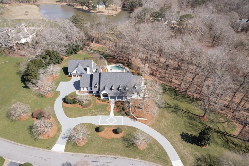 FIVE STARS !! This stunning and private 5+ acre estate is set amongst green rolling land and just a short winding trail away from a dock at your stocked lake .... all in the middle of Johns Creek! This estate which includes both a MAIN HOUSE and a GUEST HOUSE was designed to take advantage of the abundant natural light and beautiful vistas, and has just completed a TOTAL RENOVATION for both the 10K+ sf main house as well as the 2 bedroom / 2 bathroom guest house accessible via private breezeway. Immerse yourself in the elegance and sophistication of this custom-built, one-of-a-kind masterpiece that now feels like NEW CONSTRUCTION. The front porch welcomes you in and begs you to linger longer. Enter through the double doors to gleaming hardwood floors and a beautiful foyer. The banquet-sized dining room with stunning chandelier can easily seat parties of 12 or more. Work from home in the bright, spacious study. Delight the chef in you with the gourmet kitchen's expansive island, stainless appliances, huge walk-in pantry, gorgeous counters, and stylish accents. The great room with its fireplace and built-in bookcases opens to the keeping room and kitchen. Designed with both comfort and entertainment in mind, this open floor plan is light and bright and also opens to a covered screened porch and sunroom to seamlessly blend inside and outside living. The main level master suite is a haven away from the hustle and bustle of daily life with its vaulted ceiling and fireplace, beautiful spa-like bathroom, huge closet, and bonus room that can be a nursery/mom's office or second closet. The main floor is completed with a full laundry room. Upstairs, discover four secondary bedrooms with adjoining bathrooms, second laundry room, and two bonus rooms that could be a great theatre room, playroom, study room, or crafts room. The terrace level also has great spaces with an entertaining bar, media room, full bedroom with bathroom, sauna, exercise room, and play room PLUS TONS of extra storage space. The huge bonus is the full two bedroom guest house. The backyard is perfection with its beautiful landscaped grounds, azure pool, and nature walks to the lake. So much beautiful nature and the ultimate in PRIVACY but close to everything including top-ranked schools, great shopping, delicious restaurants. PERFECTION!