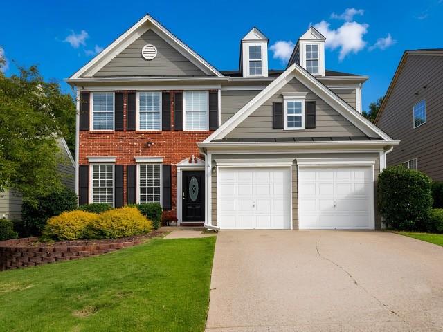 Two-story residence featuring a brick and siding facade with a double-gabled roofline