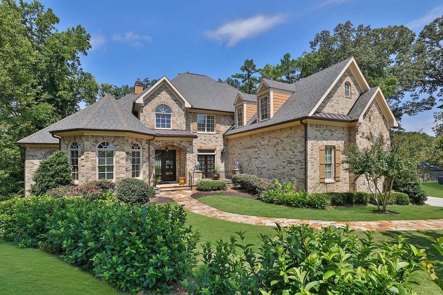Exquisite European-Style Craftsman on a culdesac lot in a Prestigious 22-Estate Enclave in the heart of Cobb County. Experience the pinnacle of luxury living in this stunning four-sided brick and stone masterpiece exuding elegance and sophistication from the moment you arrive, with a flagstone walkway leading to a welcoming rocking chair front porch and a striking custom-made iron front door. Step into a grand two-story foyer, where soaring ceilings and intricate millwork set the tone for the opulence that unfolds throughout the home. The elaborate wrought iron staircase, coffered ceilings, and gleaming hardwood floors on two levels add to the timeless appeal of this residence. Designed for both entertaining and intimate gatherings, the home features a true gourmet kitchen equipped with a complete professional Viking appliance package, an expansive island with granite countertops, a butler's pantry, a 6-burner range, and built in warming drawer. A large walk-in pantry, 60-inch refrigerator, and breakfast bar complete this chef’s dream. The kitchen opens to a sunlit fireside family room and adjacent living room with soaring 2 story ceilings and floor-to-ceiling fireplaces, offering unparalleled grandeur and comfort. The main level also boasts a private office/library adorned with floor-to-ceiling judges paneling, built-in shelving, and its own appointed fireplace, creating a perfect space for work or quiet reflection. The massive primary suite on the main level is a true sanctuary, featuring a double tray ceiling, a serene sitting area, and the home’s 4th fireplace. The en suite primary bath is a spa-like retreat, with travertine floors, dual granite vanities, an expanded separate spa shower, a Jacuzzi tub, and 2 generous walk-in closets. Each secondary bedroom offers its own en suite bath, providing privacy and comfort for family and guests alike. The partially finished terrace level houses a tiered seating movie theater and approx 1,700 square feet of space, ready to be tailored to your specific desires, all beneath impressive 10-foot ceilings. The entertainment deck overlooks a private backyard, offering a tranquil setting for outdoor gatherings or peaceful solitude. This home is outfitted with built-in speakers throughout, enhancing both indoor and outdoor living experiences. Located within walking distance of the scenic Kennesaw Mountain and just minutes from I-75, Marietta Square, Town Center, Mount Paran Christian School, Kennesaw State University, and The Avenue West Cobb, this home is ideally situated for both convenience and leisure. This estate is more than just a residence; it is a statement of luxury, exclusivity, and timeless elegance. Discover the lifestyle you deserve in this unparalleled home.
