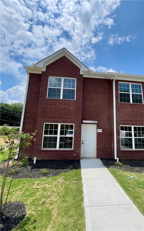 Two-story brick facade featuring multiple windows with grilles, white trim, and a prominent front entry