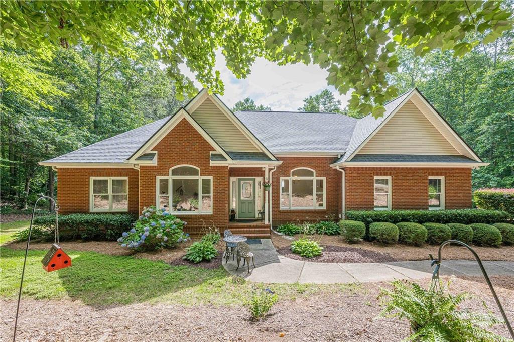 PRIVATE 4-ACRE RETREAT WITH CREEK & WORKSHOP IN THE HEART OF CHEROKEE COUNTY!! Welcome to 1498 Pinyan Lane, a stunning four-sided brick two-story home nestled on 4 private, wooded acres in a top Cherokee County school district. Enter into the home and notice the high ceilings, and light filled rooms. Pride of ownership is evident, as this home has been meticulously cared for and loved by the same family. Large dining room, extra office or flex space room, and spacious family room with stunning brick fireplace. Walk onto the new renovated back deck and enjoy the mature landscaping and large trees. Lovely granite kitchen and eat- in area, is great for family gatherings. The main level also features Master on Main with large ensuite and walk-in closet. Two spacious secondary bedrooms with Jack-and Jill bathroom. The finished basement offers a large living area, kitchenette, one bedroom, one bath, and an office (no egress). Enjoy endless possibilities with a massive 30’ x 40’ workshop (1,200 sq ft) equipped with compressor lines and 200-amp power—perfect for hobbies, projects, or a home business. The property also includes a 14’ x 35’ covered RV spot for convenient storage or travel prep. Relax by the beautiful creek with a picturesque waterfall at the lower edge of the property, or envision your dream backyard oasis with plenty of room for a pool. This rare find combines privacy, natural beauty, and practical features—all in a sought-after location close to shopping, dining, and top-rated schools. Don’t miss this opportunity to own your own private paradise!
