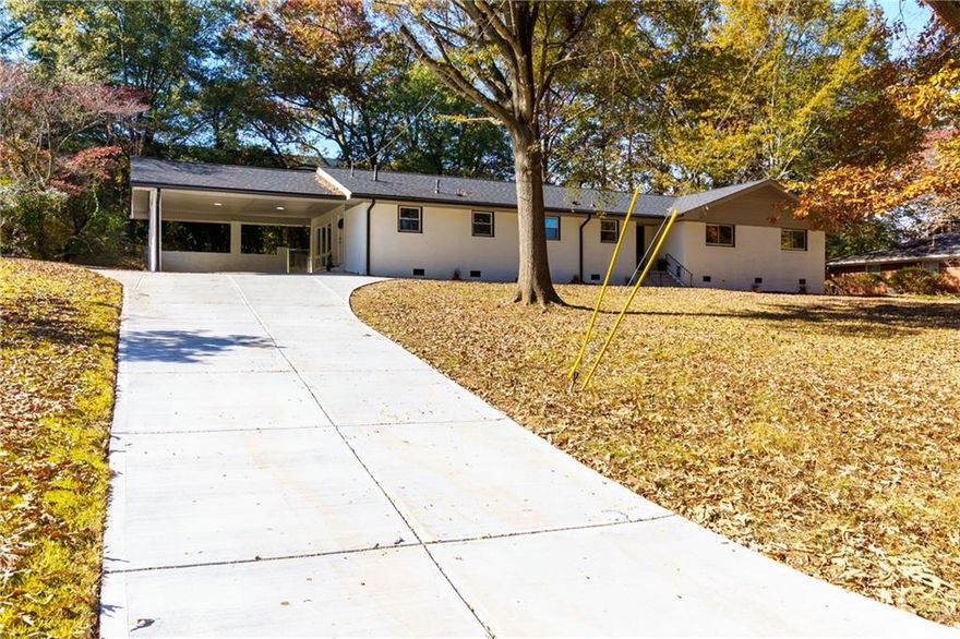Welcome to this beautifully renovated all-brick ranch situated on a spacious lot with a large front and backyard, dual driveways, and exceptional outdoor potential. One driveway leads to the covered 2-car carport, while the second provides access to additional parking and a workshop, perfect for projects, storage, or extra vehicles. Step inside to an inviting open-concept floor plan featuring the family room, dining area, and kitchen. The family room showcases a stunning marbled accent wall with fireplace, creating a sleek, modern, and elegant focal point. The dining area sits seamlessly between the family room and kitchen, offering the perfect space for entertaining with direct access to the back patio. The chef inspired kitchen is a true showstopper with white cabinetry, granite countertops, abundant storage and prep space, new stainless steel appliances including a double oven, pantry, and a center island with breakfast bar seating. Just off the kitchen, an oversized laundry room provides additional pantry/storage space for maximum convenience.
The primary suite is expansive and features a panoramic window overlooking the backyard, a sitting area, walk in closet, and a fully updated ensuite bath complete with granite countertops, double sink vanity, and a large tiled shower. Two additional bedrooms are generously sized and share an updated full bath with a shower/tub combo. A fourth bedroom offers ideal guest accommodations with its own private ensuite bathroom featuring a newly remodeled tiled shower.
Outside, enjoy a wonderful backyard with a private tree lined view, a large patio perfect for outdoor gatherings, and a separate workshop that offers endless potential; use it for storage, hobbies, or finish it out as a man cave, she shed, or studio. This fully renovated ranch offers modern elegance, functional spaces, and exceptional versatility both inside and out. Don’t miss this move-in-ready gem! 
Highlights Include: updated flooring, new, neutral paint throughout, renovated bathrooms, updated kitchen, high end finishes throughout, updated appliances, fresh exterior paint, and much more!