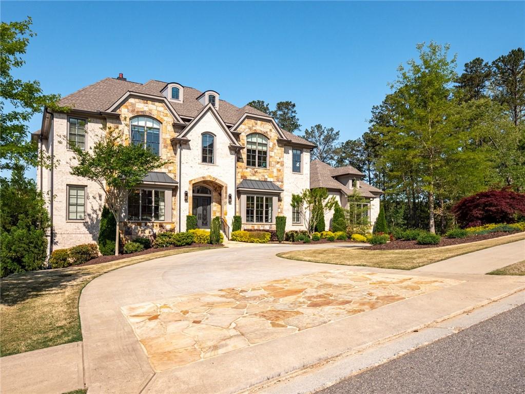 Sophisticated style and award-winning builder in Milton's popular Manor Golf and Country Club. Absolutely stunning home overlooking the 17th fairway and features soaring 12-foot ceilings, an open floorplan, owner's suite on main, covered patio with fireplace, two kitchens, finished terrace level, wine cellar, and infinity edge saline pool and two laundry centers. The main floor features a large kitchen with oversized island, marble countertops, a professional 48" gas range, and built-in refrigerator/freezer; drop zone/mud room with custom cabinet doors and sitting bench; a secondary kitchen with oven/cooktop, refrigerator, and walk-in pantry; wine cellar and bar with beverage cooler. The second floor includes four en-suite secondary bedrooms; a large open foyer and media room with built-in entertainment center, and upstairs laundry center. Terrace level features two en-suite guest bedrooms, gym, large great room with cabinetry and beverage center, golf simulator and access to the outdoor pool and patio. The outdoor area is breathtaking with limestone style pool decking, sheer decent saline pool, outdoor grill kitchen with bar seating and covered patio. Styled to perfection this home shows like a model and will certainly please the most particular buyers.