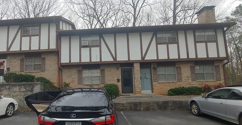 Brick facade with decorative half-timbering on the upper level, featuring multiple windows with louvered shutters