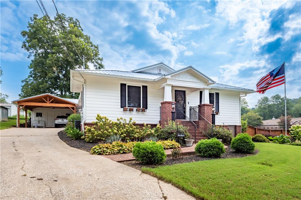 Custom remodeled 2BR / 2BA Ranch with a bonus/flex room in downtown Ball Ground just 2 blocks from main street. Open concept floor plan featuring hardwood floors, accent shiplap wall in the living room and brick accent in the kitchen.  The newly designed kitchen features white cabinets, solid surface countertops, farm sink, stainless appliances, mini beverage refrigerator, island w/cooktop, and walk-in pantry. Large bedrooms and a home office that can easily be converted to 3rd bedroom. Outdoor living at its finest with a covered deck, spacious patio, custom salt water pool, and privacy fencing. Expertly landscaped corner lot at .39 acre across from the BG post office.  Additional features include metal roof w/solar panels, tankless water heater, and multiple storage/workshop buildings.