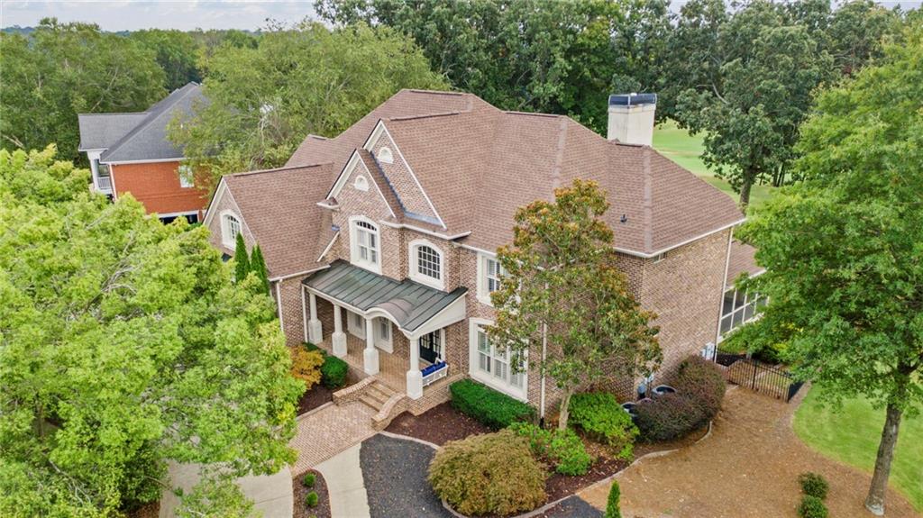Welcome to 275 Grandmar Chase, an exquisite custom home nestled in the heart of Woodmont Golf and Country Club. This former John Wieland Model Home epitomizes luxury and privacy, perfectly positioned on the 10th Tee Box of the award-winning golf course designed by the renowned Robert Trent Jones, Jr. The home offers expansive breathtaking views of the course and is conveniently located within close proximity from the clubhouse, which features restaurants, a driving range, pool, gym, and tennis and pickleball courts. The elegant design is showcased through its 4-sided brick with stucco accents and professionally landscaped grounds, complete with irrigation and lighting. A convenient fully finished 3-car garage that can be heated or cooled. A circular and side driveway complements the charming front porch, which features custom lighting and brick flooring. Step inside to discover a stunning 2-story foyer with hardwood floors and detailed millwork, all adorned with plantation shutters throughout, even in the garage. The beautifully appointed dining and living areas feature custom lighting, further enhancing the home’s elegance. The gourmet kitchen is a chef’s dream, boasting custom cabinetry, leathered granite counters, and high-end appliances. A spacious laundry room with a side porch entry adds to the home's functionality. On the main level, an office or bedroom comes complete with an upgraded full bath and access to a screen porch, providing versatile living options. The luxurious master suite upstairs offers a spa bath, custom closets, and a versatile flex room. Three additional large bedrooms offer ample closet space, with one showcasing an integrated bunk and storage system. The finished terrace level is designed for entertainment, featuring a theater room, wet bar, and a walk-out patio, leading to an oversized deck and private fenced backyard. This stunning home combines sophistication with modern amenities, presenting a move-in-ready opportunity in a prestigious community. Additionally, the home is in close proximity to shopping and highly ranked Cherokee County schools, making it an ideal choice when seeking both luxury and convenience.