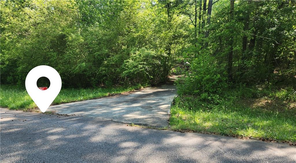 Two acreas on quiet street. Paved driveway leads up to turn around concrete pad that used to have a mobile home. Small barn with room above on the lot. Relatively flat lot at the top of the sloped drivewy. Electric and water available. Septic and Propane in the past. Do not walk up the unsafe steps to the space above the barn. Needs some clearing between the driveway and bar. 1 mile from Sun City Peachtree and 10 miles to Atlanta Motor Speedway.