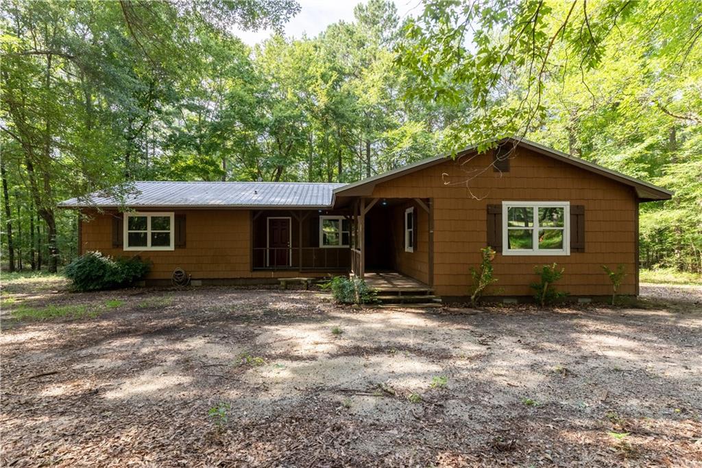 Welcome to 60 Laurie Lane, a remodeled 3-bedroom, 2-bath ranch on a private 2.08-acre wooded lot in Covington. This 1,514 sq. ft. single-story home, built in 1983, features new flooring, a new HVAC system, and a durable metal roof (approx. 10 years old) for low-maintenance living. The spacious master suite boasts his-and-hers closets and a private bath with modern finishes. The inviting living area connects to a functional kitchen equipped with a microwave, range/oven, pantry, and ample cabinetry. Double glass doors lead to a large covered back deck, perfect for entertaining or relaxing in the natural surroundings. With off-street parking and no HOA, this home offers privacy and freedom. Located minutes from Covington's historic square, restaurants, shopping and I-20, 60 Laurie Lane combines rural tranquility with urban convenience. Schedule your tour today!