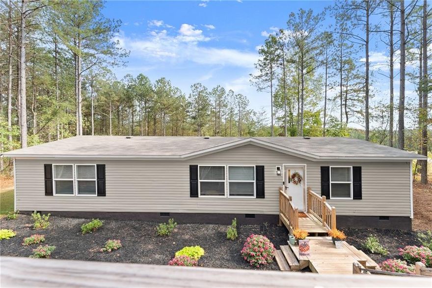 Welcome Home to Peaceful Ball Ground Living! Tucked away on 1.5 private acres in beautiful South Pickens County, this charming 3BR/2BA home—built in 2022 with no HOA—offers the perfect blend of peaceful country living and modern comfort. Step inside to find fresh interior paint, newly updated kitchen cabinets, and an open-concept layout that makes daily life easy and inviting. The spacious kitchen features an island, laminate counters, pantry, and a view to the family room—perfect for gathering with loved ones. The primary suite on the main level provides a cozy retreat with a walk-in closet and relaxing tub/shower combo. Additional highlights include laminate flooring, a convenient main-level laundry room, central electric heat and air, ceiling fans, and low-flow plumbing fixtures. Outdoors, enjoy a spacious back deck overlooking a wooded, landscaped backyard complete with a new retaining wall and a storage shed for all your tools and toys. The home sits on a permanent foundation and features a large gravel driveway with plenty of parking for guests, recreational vehicles, or extra cars. Located near shopping, scenic trails, and just minutes from Ball Ground and Canton—this is the perfect place to unwind, spread out, and truly feel at home.