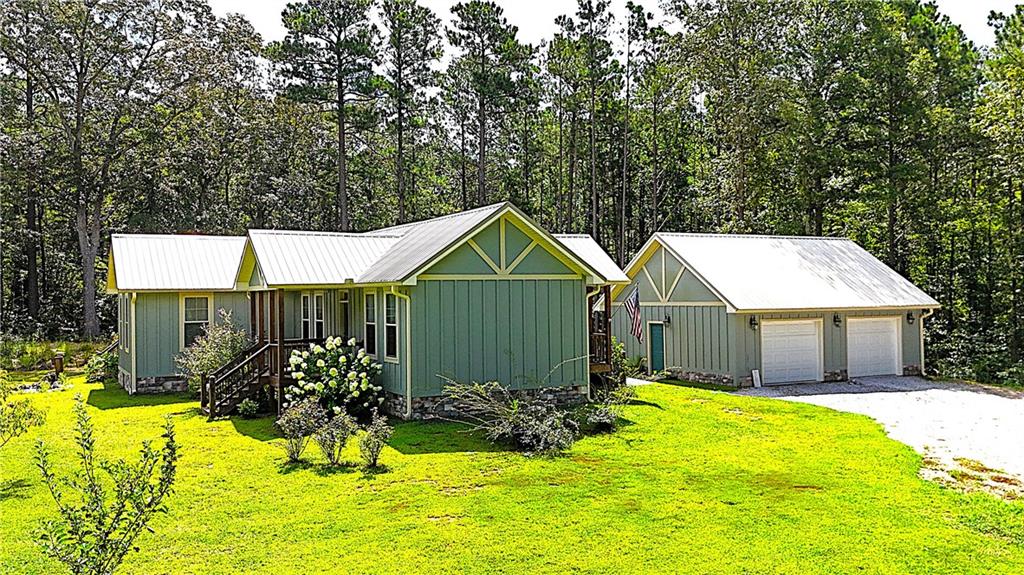Custom Home on Acreage! The owner was inspired by Aerial Images of European Cathedrals and asked the designer to draw a house plan based off that image in her mind's eye....this beautiful home is the result of that inspiration! Enter the doorway from the detached garage and the Cathedral inspiration continues, wood and stone everywhere! Soaring Vaulted Ceilings of stained wood, stone fireplace, durable LVP flooring and tons of natural light bathe this space in warmth.! Open concept defined! Living, Cooking, and Dining all in this space, the huge custom-built island with salvaged wood top looks like it's been here 100+ years, but with a microwave oven built in! Gleaming stainless-steel appliances in this chef's kitchen, Corian counter tops with glass backsplash, stainless steel vent hood over the gas cooktop....this space is just begging for the family holidays where the conversations, cooking and laughter fill this space with the sounds of joy and love! At the end of this fellowship space, walk through the giant barn doors to enter the "quiet part" of the home! The hallway off the common area maintains the cross-like architectural design of the home, with the secondary bedrooms at opposite ends of the hall and the master suite just ahead! Enter this area into your own private sanctuary! The large master bathroom with soaking tub and enormous walk-in closet are just part of the incredible space....just through a second set of barn doors, is the private study or sitting room that makes you want to curl up with a warm blanket and a great book to unwind! With tons of windows and a glass door heading out to your private back deck, this space might be the best spot in the house to seek a little serenity and solitude. The current owner uses the adjoining room as an art room but put up a door and a closet door and it is the 3rd bedroom. At the other end of the hall is the other bedroom and full bath which feels as though it's on its own "wing" of the house, again with high ceilings and tons of windows this bedroom is spacious yet private and cozy! Step out the doors in literally every direction and the surroundings are as inspiring as the stuning home! Tucked into a 6.5 acre wooded parcel at the end of the winding gravel path this place is a hidden little piece of heaven! The circular driveway is anchored by a great 2-car detached garage or workshop, with the interior walls and ceilings wrapped in durable metal, cabinets with a sink, and it even has a bathroom! Truly a "one of a kind", the property has great details that may not be immediately noticable, such as a small koi pond, fruit trees, specimen plantings, and multiple porches and nooks, outdoor areas, mature pines all of which together make this home feel like it has been here for decades but with all of the modern conveniences and efficiencies of a home that is less than 6 years old! Ideal home for the retirees wanting to downsize to single floor living, or perfect for the young family that is looking to escape the subdivision lifestyle and discover a new way to LIVE!!!