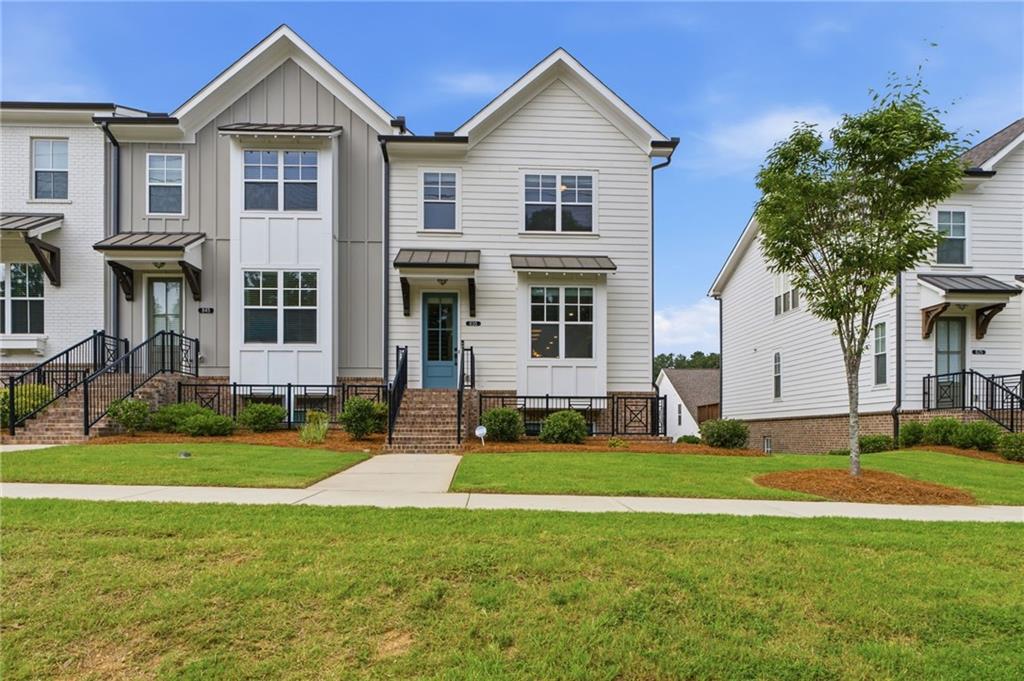 Modern townhome exterior with white siding, black window awnings, and a gabled roofline