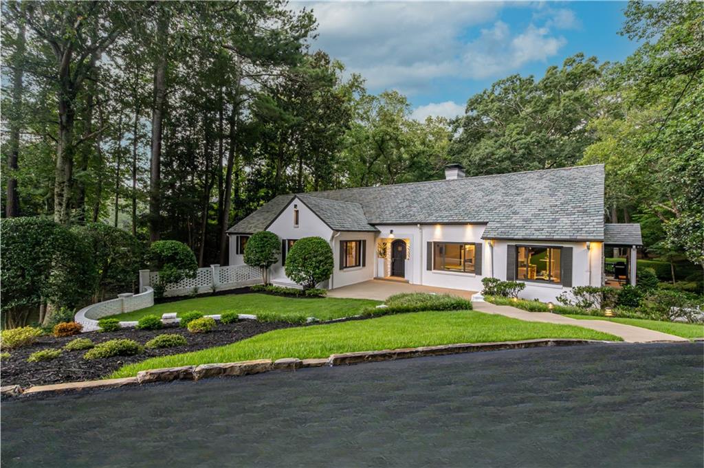 Tucked within a beautifully manicured setting, this timeless 1950 residence - topped with a Vermont slate roof - has been artfully transformed into a modern sanctuary through meticulous renovations completed just 3 years ago. Spanning over 5,000 square feet, this home reflects refined taste, thoughtful design, and luxurious comfort. A grand welcome begins in the foyer, where newly refinished hardwood floors in a classic herringbone pattern set a tone of timeless sophistication. From here, the main level unfolds into a series of light-filled living spaces—each room seamlessly connected yet distinct in character. Anchoring the home is a professionally appointed chef’s kitchen, recently enhanced with quartzite countertops. Designed for both the culinary enthusiast and the entertainer at heart, the space features a Sub-Zero refrigerator, ZLINE natural gas cooktop, and dual electric ovens. Adjacent to the kitchen, a generously sized laundry and utility room provides additional practicality, complete with a full-size refrigerator and freezer. Also located on the main level is a versatile office—ideal for a sophisticated home office, quiet reading room, or inspired creative studio. The primary suite is a private sanctuary, intentionally designed to promote wellness and serenity. A custom dual sauna—featuring both electric and infrared elements—invites daily restoration, while the expansive spa-inspired bath offers a deep jetted soaking tub, a walk-in shower with rainfall head and body jets. Completing the suite is a thoughtfully designed, custom walk-in closet. Two additional guest suites on the main level are generously proportioned, each featuring its own private bath. An expansive elevated deck overlooks the backyard, ideal for grilling and outdoor entertaining. As you descend the staircase into the fully finished terrace level, you’re welcomed into a luxurious extension of the home. A state-of-the-art home theater, complete with a built-in surround sound system and projector, sets the stage for immersive cinematic experiences. Nearby, a well-equipped private gym offers the convenience of at-home wellness, while a secondary flex room presents an opportunity for a fifth bedroom. A dedicated office space exudes a rich, moody ambiance—ideal for focused work or study. For extended guests or multigenerational living, a private suite offers comfort and privacy. The heart of this level is an entertainer’s bar area, featuring a striking waterfall-edge leathered granite island with integrated mini refrigerator and dishwasher, complete with its own living area anchored by a custom stucco gas-starting fireplace. Step outside to an oversized patio—perfect for entertaining guests or enjoying quiet evenings outdoors. At the rear of the property, a two-story barn with electricity invites countless possibilities. With dual HVAC systems and two natural gas water heaters, climate control and hot water access are never in question. A whole-home 22kW Generac generator ensures uninterrupted living and protection from unexpected power loss—ideal for modern demands. The property is fully serviced by two independent irrigation systems that cover both the front and backyard—including the barn area—ensuring lush greenery year-round. Designed by award-winning interior design firm A SPACE Home Design, this home has been prominently featured in Architectural Digest, Modern Luxury Interiors Atlanta and The Atlantan. It has also served as a filming location for a celebrity music video and a major Amazon TV production—demonstrating its appeal as both a private retreat and a high-demand filming location, with potential for future rental income. With refined interiors, wellness-focused amenities, advanced systems, and outdoor spaces that inspire, this move-in ready home is perfectly suited to today’s discerning buyer seeking a property with timeless appeal and enduring value.