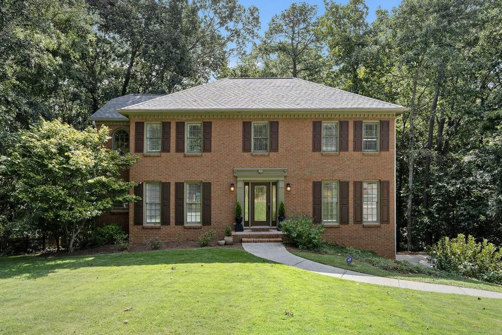 Traditional Brick Beauty in Bentley Place near Berkeley Lake in Peachtree Corners! Welcome to this charming Brick Home tucked on over half an acre in the tranquil and established Bentley Place neighborhood. From the moment you arrive, the Curb Appeal is Impeccable with a Large Grassy Front Yard, timeless brick fa ade, dark shutters, and a welcoming entry framed by mature trees and lush landscaping. Step inside to be greeted by Dark Hardwood Floors, Crown Molding, and a spacious entrance Foyer. To your left, a Formal Dining Room sets the stage for hosting and memory-making, leading seamlessly into the Chef's Kitchen complete with Granite Countertops, White Cabinets with open shelving, Stainless Steel Appliances, and a Breakfast Nook Wrapped in Windows with peaceful views of the Backyard. The heart of the home is the Fireside Family Room, featuring an Elegant White Mantel and Custom Built-Ins. The main level also offers a dedicated Home Office or Flex Space, Laundry Room, and convenient Powder Room. Upstairs, retreat to the expansive Primary Suite with a Walk-In Closet and En-Suite Bathroom boasting a Soaking Tub, Double Vanity, and separate Glass Shower. Three Additional Bedrooms share an updated Full Bath with a stone vanity and stylish tile finishes. The Daylight Terrace Level provides Two Versatile Bonus Spaces perfect for a Gym, Playroom, Media Room, or Second Office. Outdoors, a Spacious Deck overlooks the large, private backyard with a balance of wooded privacy and grassy play areas, ideal for relaxation or entertaining. Shaded by mature hickory trees, the backyard offers seasonal nut harvests and a beautiful natural backdrop featuring hummingbirds, deer, turtles, squirrels, and chipmunks. A Two-Car Garage completes this wonderful home. Located in the sought-after Berkeley Lake Elementary district, just minutes from The Forum on Peachtree Parkway, Golf, the Chattahoochee, and quick access to I-285 and I-85, this home blends Classic Charm with Modern Convenience in a serene yet accessible location.