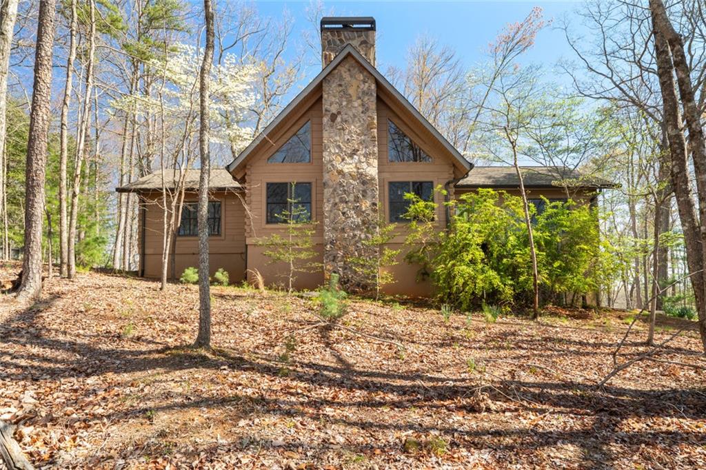 Log cabin fans Welcome to this charming, one-owner-owned log cabin that offers the perfect blend of rustic character and modern convenience. Thoughtfully maintained over the years, this home is designed for easy main level living and is ready to create new memories for its next owners. Greeted by the striking tortoise glass front door, you’ll step into an inviting open concept living space featuring warm wood walls, exposed beams, and large picture windows that flood the space with natural light. The wood-burning fireplace takes center stage in the living area, adding both warmth and charm to the heart of the home. The spacious layout includes a generous kitchen with a newer refrigerator and custom, hand-crafted backsplash tiles by a talented NC artist. A cozy loft above provides additional living, sleeping or workspace, while a flex room and ample storage options are located on the lower level, offering endless possibilities to suit your needs. 2290sf finished upstairs + unfinished sf downstairs. The outdoor living spaces are just as inviting, with a large, screened porch and an open deck with steps leading to a flat, expansive backyard—perfect for enjoying the outdoors. The oversized 2-car garage features new doors and has ample room for a work area. Recent updates include a new roof, chimney cap, fireplace firewall, screened porch screening, and more! ensuring peace of mind for years to come. Just two minutes to the main gate and a short drive to Big Canoe’s amenities, this home is ideally located to enjoy both privacy and convenience. This cabin has been a place of cherished memories for the current owners - now it’s time for you to make it your own! *Buyer to verify all information and dimensions deemed important.