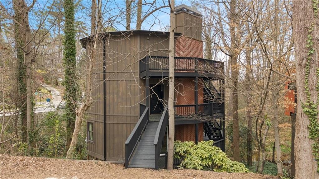 Located in the covetable Collier Hills neighborhood adjacent to Bitsy Grant Tennis Center, Bobby Jones Golf Course, and The Beltline’s Northwest Connector Trail, this one-of-a-kind landmark home combines photo-worthy design with luxurious finishes offering a sophisticated living experience in an Atlanta icon. Renovated down to the studs, and expanded by 730sqft, every inch of this home has been meticulously designed, from its stunning architectural form to its hand-selected finishes. The striking 12- sided Deltec design maximizes space and light, while the open-concept floor plan invites seamless flow between the entertaining and living areas.
A three-story deck wrapped around the home provides lush views of the creek and greenbelt behind the house. This home offers the perfect proximity to the best Buckhead and Midtown have to offer, and a dream for any outdoor enthusiast. The interior has been customized with no detail spared to be an entertainer’s dream. Featuring a giant kitchen island clad in imported Rosso Levanto leather- finished countertops, perfect for cooking and entertaining, the kitchen is outfitted with bespoke solid-ash cabinetry that wraps the wall, a custom color-matched double oven and 8-burner, and a unique custom-cast brass pot rail to add function and style. Small appliances and the refrigerator are modestly tucked away in the luxurious walk-in pantry with custom cabinetry. The expansive primary bedroom and bathroom serve as a serene and spacious sanctuary on the top level, featuring endless natural light, penthouse views of the natural surroundings, and hand-mosaic Emperador marble floors in the spa-like bathroom. The lowest floor is a moody den, with a custom-fitted sofa nested in a curved alcove to anchor the space. Flanking this room is two well-appointed spare bedrooms with Jack-and-Jill marble bathroom and pass-through closet. Each floor is punctuated by a continuous three-story fireplace, finished with handmade brick tiles serving as a striking focal point of the home, bringing warmth to each floor.
The combination of modern design elements, designer finishes, natural surroundings, and eco-conscious features makes it a standout property in one of Atlanta’s most desirable neighborhoods. This home is a rare opportunity to own a piece of architectural significance combined with one of the best locations for serene Intown living. Furnishings can convey with the property upon request. Don't miss your chance to make this creative home your own.