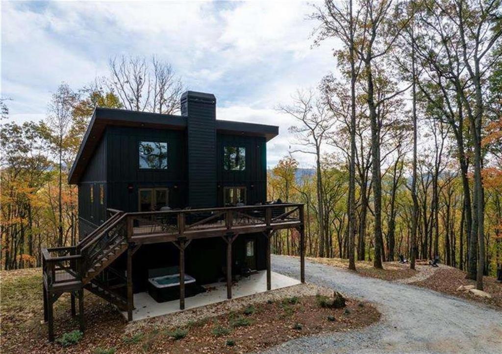 Nestled within the North Georgia Mountains, this property provides a peaceful retreat. Suitable for either a full-time residence, secondary home or investment property- it is sure to impress. The main floor boasts an open family and dining room with pine floors and an oversized woodburning fireplace. The kitchen is equipped with Black Stainless appliances, stone backsplash, and leathered granite. The primary suite features a tiled shower, separate soaking tub, and electric fireplace. The upstairs loft is ideal for relaxation with two full-sized beds and stunning views. The lower level features a second living area/media room with a third full bathroom. A bedroom with a queen-sized bed is perfect for guests. The bunk room currently accommodates two queen-size beds and two twins. A metal roof perfectly complements the exterior finishes and provides a soothing sound on rainy nights. Situated on 2.13 very secluded acres on a private, gated road. Enjoy the beautiful sunsets from the front porch or hot tub!
