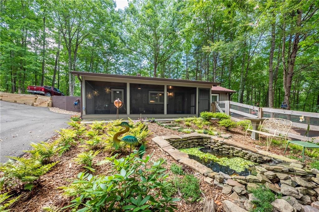 Get ready to be surprised by this recently renovated 2 bed, 2 bath mountain home on 1.5 acres. All renovations, including new asphalt driveway, have been completed in the past 2 years. This charming home is surrounded by picturesque woods, yet it is less than 15 minutes away from the interstate, grocery, retail stores and restaurants. Drive down your own private road to a view of a newly built pond with waterfall. Relax inside a large recently built screened porch overlooking koi pond, hardwood trees and beautiful mountain sunsets. Have pets or chickens? This house is for you with a new fully fenced yard which is accessible directly from the house, screened porch or two fence gates. Now, walk inside into a cozy open floor plan living room that boasts metal and wood-plank ceilings, reclaimed wood throughout home, stacked stone gas fireplace and a breathtaking fully renovated kitchen. Kitchen includes all brand new high-end soft close cabinets, quartzite counter tops, a fabulous farmhouse copper sink and top-end stainless steel appliances, including a two-drawer under-the-counter refrigerator with additional room in adjoining laundry room for a full size refrigerator and freezer. There is a separate dining room right off kitchen and four skylights bring lots of natural light inside. Two cozy bedrooms each have their own private en-suite. House includes all new Andersen doors and windows which keeps it cool in summer and warm in winter. There is also a separate laundry room and a spacious shed for extra storage. Recent landscaping enhancements include landscaped front yard with pond, a new asphalt driveway and retaining wall with steps that lead to extra parking. HVAC is new, including a full house de-humidifier. Newer roof and all new lighting throughout home. No HOA. Come see this amazing home and be prepared to fall in love!