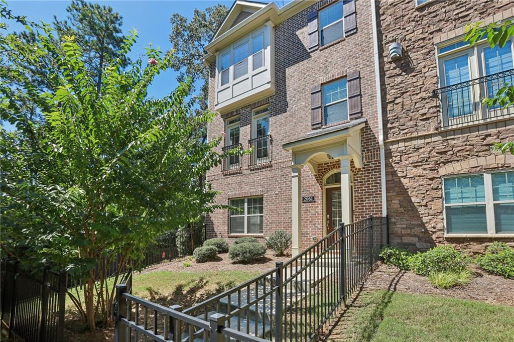 Beautiful Move-In Ready Townhome in Gated Community! This bright corner-unit townhome offers the perfect blend of style, function, and convenience. A private gated entry and front yard welcome you inside. The first floor features wood floors, a bedroom with a full bath—ideal for guests or a home office—and access to the two-car garage. Upstairs, the open-concept main living area features a light-filled living room with a fireplace, a modern kitchen with an oversized island, stone counters, tile backsplash, stainless steel appliances, and a dining area with balcony access. On the third floor, the spacious primary suite includes a tray ceiling, walk-in closet, and spa-like bath with dual sinks and an oversized fully tiled shower with bench. Two additional bedrooms, a full bath, and a convenient laundry room complete the level. Enjoy outdoor living on your private balcony or at the community greenbelt with fire pit and pool. Located near shopping, dining, and with easy highway access, this home truly has it all!