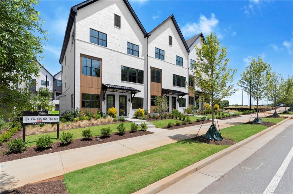 Welcome to The Anniston at The Gathering, a stunning Contemporary style townhome designed for modern living. This beautifully crafted home offers 1,644 square feet of thoughtfully designed space, features two bedrooms, a flex space, and three luxurious bathrooms, perfectly blending comfort and style. As you enter the Anniston you will find a versatile terrace level that includes a cozy flex space, a full bathroom, and convenient access to the garage. Ascend to the main living area on the second floor, where 10-foot ceilings and an open-concept layout seamlessly integrates the kitchen, dining area and living room. The gourmet kitchen showcases quartz countertops, KitchenAid appliances and maple cabinetry. This space is perfect for entertaining guests or enjoying a quiet evening at home. Step out onto the covered deck off the living area to enjoy fresh air and outdoor relaxation. The third floor is dedicated to restful retreats. The primary suite boasts a walk-in closet and a well-appointed bathroom featuring double vanities, quartz countertops and a glass shower providing a serene sanctuary. A second bedroom, complete with its own full bath, offers comfort and privacy for family members or guests. The Gathering is a vibrant new community, just minutes from downtown Alpharetta, Avalon and top-rated schools. Walk out your front door and hop right on the popular Alpha Loop. Enjoy our community amenities such as a Community Garden, Firepit and Dog Park. This home provides the ultimate modern suburban living. Experience the perfect combination of style, comfort and convenience!! This home is MOVE-IN READY!! Agent is on-site Monday, Tuesday & Saturday (10:00-6:00) and Wednesday and Sunday (1:00-6:00). Photos are a representation of floorplan and design selections will vary.