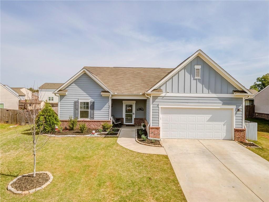 View of front facade with board and batten siding, brick siding, driveway, and an attached garage