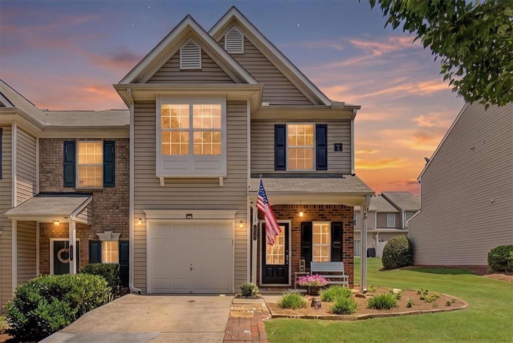 Two-story residential exterior featuring a combination of brick and siding, an attached garage, a covered front entry, and a bay window