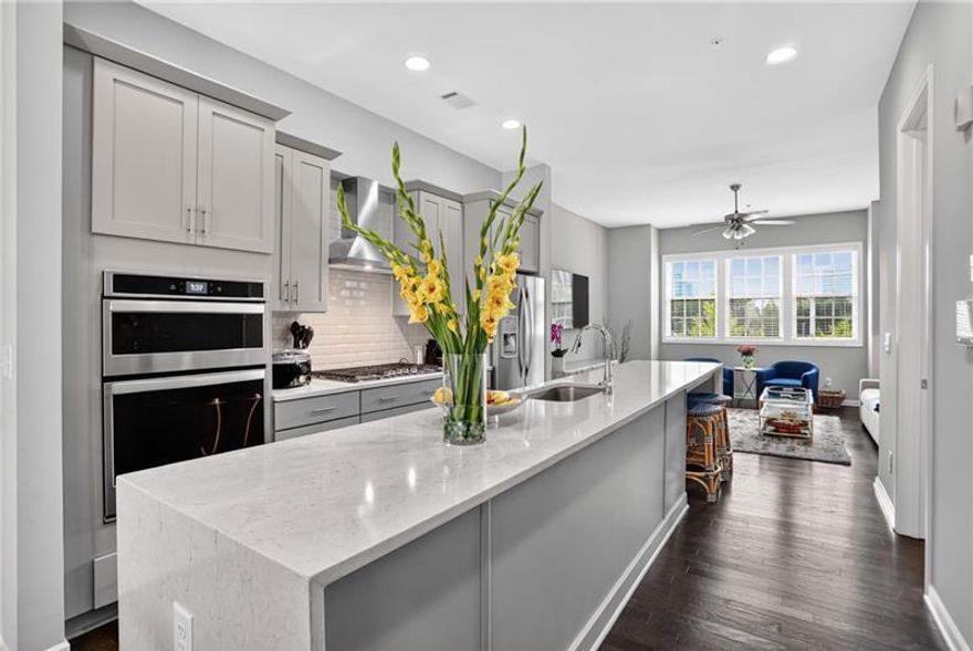 Discover this stunning 2-bedroom, 2.5-bathroom townhome in the heart of the highly coveted community of Aria South in Sandy Springs, perfectly situated within walking distance to MARTA, upscale shops, top restaurants, and the Mercedes-Benz headquarters. Nestled in a boutique building of only five units, this home offers a rare combination of privacy, convenience, and designer finishes.   Step inside through the foyer to find pristine hardwoods throughout all three levels. Upon entry discover a versatile secondary bedroom with a full en-suite bath, ideal for guests or a home office. The main level boasts an open-concept floor plan with a spacious living room, dining for four, and a gourmet kitchen featuring upgraded Wellborn cabinetry, stainless steel appliances, a dramatic stone waterfall island, and designer lighting. A stylish half bath and a private balcony complete this level, offering the perfect flow for everyday living or entertaining.   On the upper floor, retreat to the expansive primary suite, complete with a luxury bathroom showcasing dual sinks, abundant counter space, an oversized shower, a separate water closet, and a generous walk-in closet with full-size washer and dryer.  One of the home's most unique features is the oversized tandem garage, offering an additional alcove perfect for a home gym or secondary office space. The quiet community also includes a sparkling pool, ideal for warm summer days.  With its unbeatable location just off GA-400, you'll enjoy easy access to everything Sandy Springs and Atlanta have to offer-making this property the perfect blend of comfort, style, and convenience.