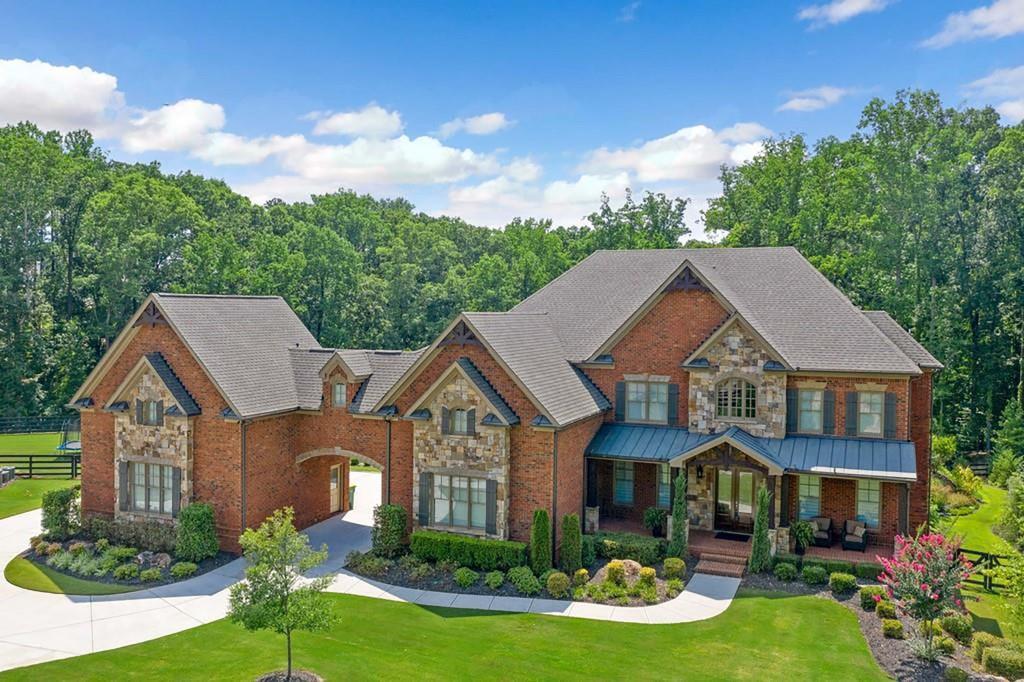 Set on a private, wooded 4.2+/- acre lot in Milton's prestigious Triple Crown community, this exquisite full-brick estate blends timeless architecture with modern sophistication. A graceful porte-cochere leads you to a thoughtfully designed layout originally crafted by renowned builder Tommy Fuqua. The home features a gourmet Thermador kitchen, expansive living spaces, and a lavish primary suite with a spa-inspired waterfall shower and custom dressing room. A separate au pair or in-law suite offers complete privacy, ideal for multigenerational living or long-term guests. The newly renovated terrace level includes a sleek bar, wine room, fitness suite, and private guest quarters. A screened-in back porch overlooks the Pebble Tec saltwater pool and professionally installed basketball court, while the outdoor spa comfortably accommodates up to 8 people creating a resort-style retreat perfect for both relaxation and recreation. With impeccable finishes, soaring ceilings, and proximity to top-rated schools, Crabapple Market, and downtown Alpharetta, this home offers an unparalleled lifestyle in one of North Georgia's most coveted neighborhoods.