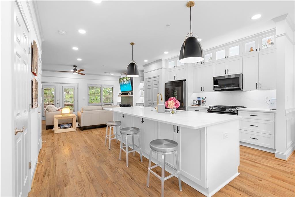 MAJOR PRICE REDUCTION ON COMPLETELY RENOVATED Luxury End-Unit Townhome – Walk to Downtown Alpharetta & Avalon! Perfectly situated in the heart of Alpharetta, this stunning 4-bedroom, 3.5-bath 2 car garage fee-simple townhome offers an unbeatable combination of location, modern upgrades, and thoughtful design. Just steps from downtown, Avalon, top restaurants, shopping, parks, and The Alpha Loop, this home provides both convenience and elegance. Inside, three levels of beautifully refinished living space feature rich 3/4-inch hardwood floors throughout, including both staircases. The completely renovated kitchen is a true showpiece, with brand-new cabinetry, a striking 13-foot custom island with extra storage, quartz countertops, and black stainless steel appliances. A custom-designed walk-in pantry with hardwood organizers ensures effortless organization, and a second pantry for additional storage. The spacious dining area flows seamlessly into the inviting family room, where a modern tiled fireplace is flanked by custom built-in bookcases. The primary suite feels like a private retreat, with its raised ceiling, custom closet system, and a fully remodeled spa-like bath featuring new tile walls, vanities, countertops, and fixtures. Each additional bathroom has been updated with high-end finishes, including new tile, sleek vanities, and designer lighting. The entry-level suite offers a large bedroom with an en-suite bath, perfect for guests or a private home office. Every inch of this home has been designed for comfort and style, with custom color-matched interior shutters on every window, upgraded lighting throughout, and an extended deck with a covered overhang—ideal for outdoor entertaining. The newly renovated laundry room features custom cabinetry and designer tile, while additional custom storage solutions enhance both the master bedroom and bathrooms. New HVAC, three-sided brick construction, and refreshed exterior lighting complete this move-in-ready masterpiece. With luxury upgrades, impeccable design, and a prime walkable location, this townhome is a rare opportunity in Alpharetta. HOA includes water/sewer and trash service! Don’t miss your chance to make it yours!