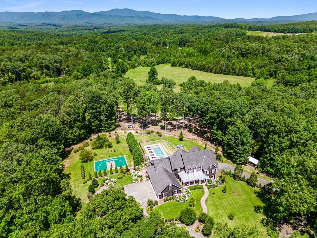 Welcome to this timeless private mountain estate on 23 acres in Blue Ridge, Georgia. Located just minutes from downtown Blue Ridge on all flat paved roads, enter through automated gates down the private tree-lined driveway unveiling the four-bay car barn (additional 3 car attached) and stunning 10,000 sq foot completely renovated and fully furnished home. Take in the incredible scenery of the pool, landscape, pasture, creek and beyond to the endless mountain views of the Cohutta Wilderness. The home and grounds underwent a significant renovation and enhancement over the past year including: exquisitely furnished with high end designer furniture, art, lighting, rugs, wallpaper, and decor; new basement level custom kitchen and bar; full gym and game room, spa room with infrared sauna; updated main level chef's kitchen; updated bathrooms; new paint throughout; custom wallpaper treatments; all new light fixtures, led can lights and ceiling fans; Sonos system; new spring fed well pump and pipes with whole house water filtration; two electric car chargers; and new powered entry gates with camera and app control. The exterior and grounds underwent a significant transformation as well, including: complete re-staining and painting the exterior; tree removal and landscaping design to gain complete privacy and spectacular views of the Cohutta Mountain Wilderness; new Sport Court with pickleball, volleyball, badminton, and basketball that could also be used as a helicopter pad; 15x50 heated saltwater pool and spa with pebble tec, commercial gas heater, Indiana limestone pavers, and RH teak furniture; Barn, chicken coop and fencing for animals; and hiking/ATV trails throughout the property. Located just 10 minutes from downtown Blue Ridge or McCaysville, 25 minutes to Blairsville private airport, 25 minutes to Ellijay, and 1.5 hours to Atlanta. The possibilities for this property are limitless: equestrian, family compound, corporate retreat, wedding venue, bed/breakfast, wellness retreat, and more. This estate is unmatched for its combination of location, acreage, square footage, renovation, furnishings, amenities, privacy and views.