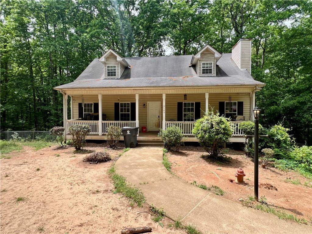 Ranch-style residence featuring a covered front porch with white railings, dormer windows, and a prominent chimney