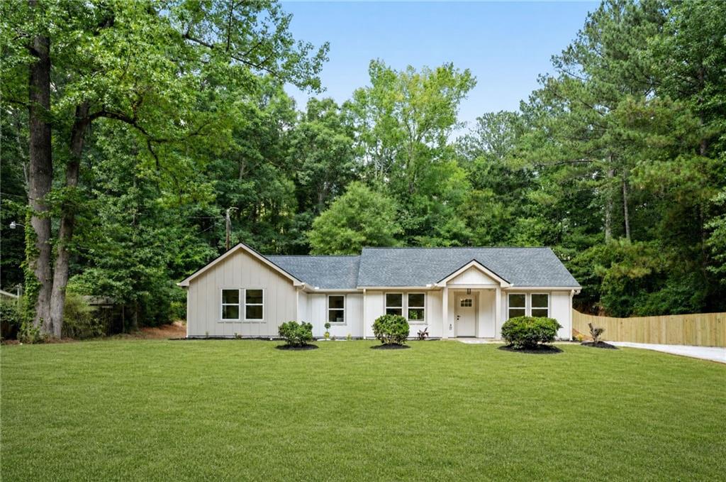 Ranch-style residence featuring a prominent front lawn, a covered front entry, and a gravel driveway