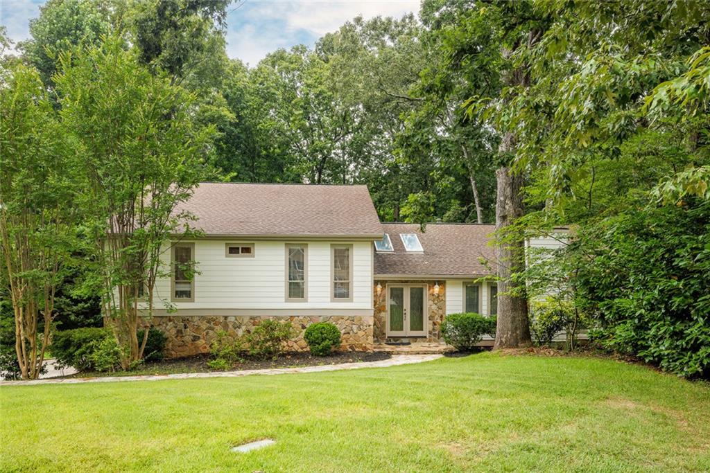 Welcome to this beautifully updated split-level home nestled in the highly sought-after swim and tennis community of Woodland Forest. Perfectly situated on a quiet cul-de-sac, this property boasts lush, mature landscaping and towering trees that create a private, serene setting. Step through elegant leaded glass double doors into the soaring two-story foyer, where skylights and a tongue-and-groove wood ceiling set a warm and welcoming tone. The bright and airy living room features a vaulted ceiling and striking stone fireplace, flowing seamlessly into the vaulted dining room with sliding glass doors that open directly onto an expansive new deck—ideal for entertaining or enjoying peaceful mornings overlooking the private, fenced backyard. The updated gourmet kitchen is a chef’s dream, featuring rich stained cabinetry, granite countertops, tile backsplash, gas cooktop, breakfast bar, a dedicated computer desk, and a double pantry. The adjoining breakfast room offers a perfect place to gather, with convenient access to the outdoor living space. Upstairs, the oversized owner’s suite provides a luxurious retreat with a fully renovated spa-inspired bath featuring dual vanities, a frameless glass shower with dual shower heads, and a large walk-in closet. Two spacious secondary bedrooms share a beautifully appointed hall bath. The versatile lower level includes a fourth bedroom and full bath, along with a cozy, paneled family room that walks out to the lower patio and level backyard—perfect for guests, multi-generational living, or a private home office setup. Gleaming hardwood floors flow throughout the home, and the garage includes a dedicated workshop area for added functionality. Residents enjoy private, walkable access to the neighborhood pool, tennis courts, and playground, along with a premier Sandy Springs/Dunwoody location just steps from Woodland Elementary, Dunwoody Village, shopping, dining, and entertainment. With quick access to GA-400 and major interstates, this is truly an exceptional opportunity to enjoy the best of both lifestyle and location
