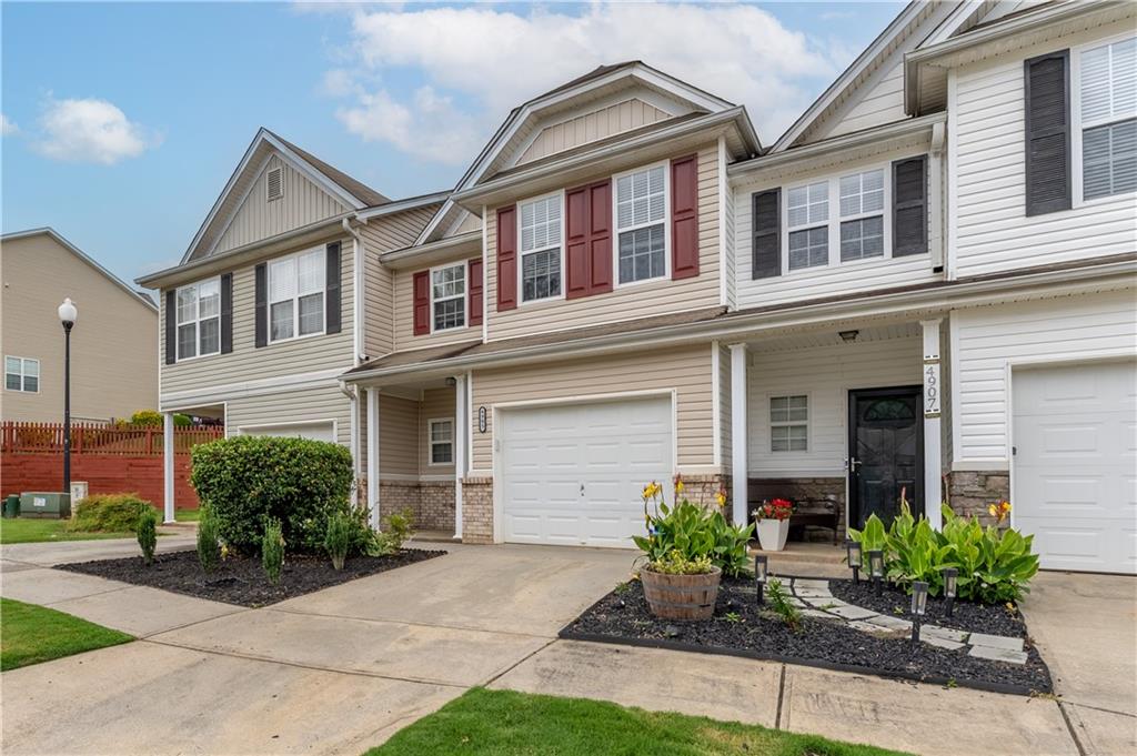 Craftsman house featuring an attached garage, covered porch, driveway, and brick siding