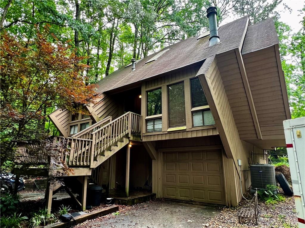 Calling all artists, visionaries, and lovers of the wonderfully unexpected—welcome to 2965 Pond View Ct, a truly unique contemporary diamond (literally!) in East Cobb. This is no cookie-cutter house. Designed and built by Tom Mozen—a local builder known for his bold, architectural creativity and his motto of never building the same home twice—this was the very first neighborhood he developed in East Cobb. And he made sure to start with a statement.
From the moment you arrive, you’ll notice the daring angles and striking shape of this diamond-shaped split-level home, tucked at the end of a quiet cul-de-sac on a private, wooded lot. Step inside and you’re greeted with an architectural centerpiece: a spiral staircase suspended by cables, leading to a private primary suite perched above the rest of the home. This suite includes a full bathroom and opens to a covered deck overlooking the backyard—an ideal retreat to sip coffee, read, or create.
On the main level, you’ll find two additional bedrooms and a full bath, with plenty of natural light and potential to update or reimagine. The unfinished lower level offers room to expand, with the potential for another bedroom, bath, studio, or media space. There’s also a two-car garage, and the shared driveway adds a touch of old-school charm to this hidden enclave. Ideally located in the heart of East Cobb, this home is just a short walk to top-rated Pope High School and zoned for some of Cobb County’s highest-performing public schools, with convenient access to shopping, dining, parks, and major highways like I-75 and GA-400—making everyday errands and commutes a breeze.
This home is being sold AS IS and is perfect for someone with vision, creativity, and an appreciation for bold design. It’s not just a house—it’s a conversation starter. If you’ve been searching for a fixer-upper with personality and serious architectural chops, this is the one.