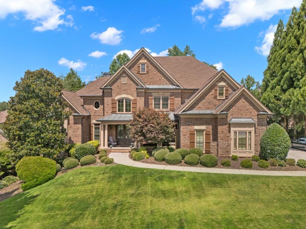Welcome to luxury living in this stunning four side brick home perfectly positioned on the 6th hole of the prestigious Jack Nicklaus Signature-designed Bear's Best Atlanta Golf Course. Located in a gated, swim/tennis community in the sought-after North Gwinnett School District, this exceptional residence offers comfort and elegance. A charming covered front porch welcomes you home. Opening to a beautifully designed home filled with natural light. The twostory great room features a dramatic wall of windows, built-in bookcases, and a sweeping double staircase that sets the tone for sophistication throughout. The primary suite on the main level is a serene retreat, complete with a sitting area, his and her walk-in closets, and his and her water closets for ultimate convenience and privacy. Entertain in the elegant formal dining room or enjoy casual meals in the spacious keeping room and breakfast area, both open to a chef's kitchen with white cabinetry, stone countertops, stainless appliance, island, and an oversized bar perfect for gatherings. Step out onto the covered deck overlooking a fenced private backyard-a perfect spot for morning coffee or evening relaxation. Upstairs, you'll find a second primary suite, two additional generously-sized bedrooms-each with their own private bath and large closet, plus a library loft and an additional loft area with built-in desk, ideal for work or study. The large finished terrace level is an entertainer's dream, featuring a media room, bar, family room, gym, bedroom, full bathroom and walk-out access to the backyard. With 5 bedrooms, 5.5 baths and a well-appointed mudroom off the three-car garage adds everyday practicality. A thoughtful design to details throughout, this home is the epitome of luxury living in one of Atlanta's most desirable golf communities. This home is more than a residence, it's a lifestyle.