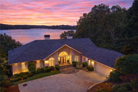 Lakefront single-family residence at sunset, showcasing panoramic views of Lake Lanier, landscaped yard, and inviting entryway, emphasizing recreational lifestyle and serene living.