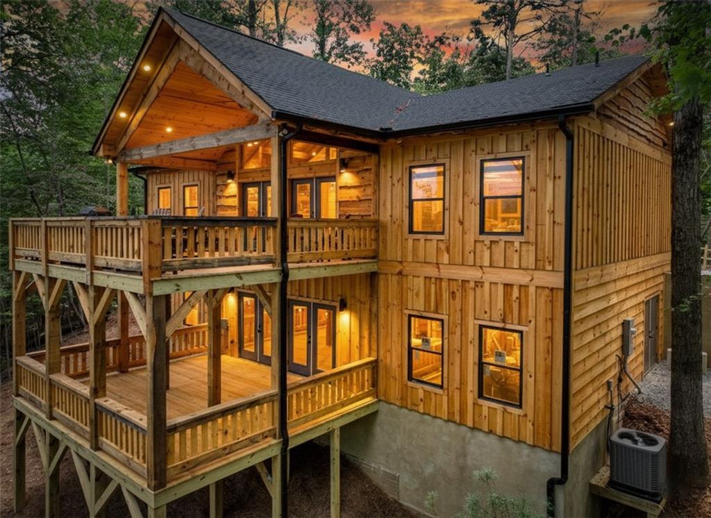 NEW CONSTRUCTION - Welcome to "Black Bear Pine Retreat" - Perfectly situated on 2.48 ACRES with a protected long range MOUNTAIN VIEW of the Cohuttas, this brand-NEW custom cabin blends rustic charm with luxury detail at every turn. Step inside to soaring cathedral ceilings with exposed beams and pegs for a true timber-frame feel, anchored by a stunning 12' Tennessee fieldstone fireplace with a craftsman beam mantle. The thoughtful design continues throughout with layered trim, live-edge accents, custom wainscoting, and tailored cedar closet systems. The primary suite offers a clever pass-through to the laundry area, while the kitchen showcases shaker cabinetry, chiseled cream granite, tumbled travertine backsplash, GE appliances, and a walk-in pantry. A full unfinished basement (plumbed for expansion to include bath, kitchen, & radon) & framed to accommodate a garage if desired. Outdoors, expansive party porches with rough-sawn timbers, live-edge details, and a wood-burning fireplace create the perfect gathering spaces (already pre-wired and supported for a hot tub). Practical features include tankless water heater, city water, generous parking with level driveway & split rail fencing, and short-term rental eligibility. Located in a popular river resort community, with numerous amenities & where ATVs, golf carts, and side-by-sides are welcome (w/permit). Private yet convenient, this property offers both an inviting retreat and a smart investment.
