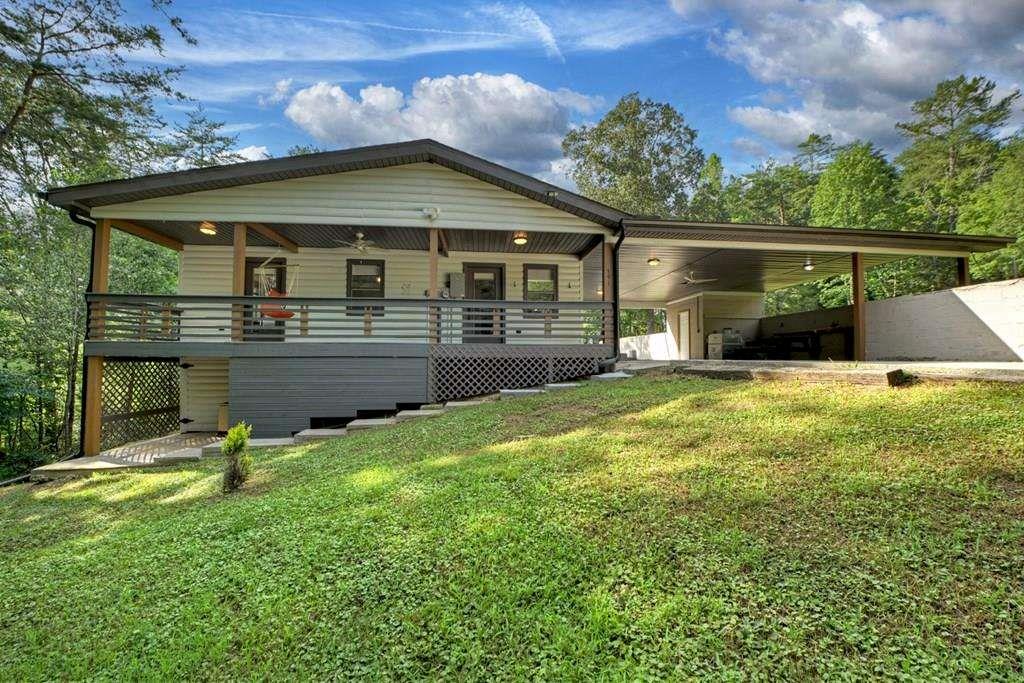 Discover exceptional value on 2.65 acres of unrestricted North Georgia land-just minutes from downtown Blue Ridge. This tastefully updated three-bedroom, two-bath home greets you with a welcoming front porch and features an open-concept layout with gleaming new hardwood floors, vaulted ceilings, and abundant windows that bathe the living spaces in natural light and frame tranquil forest vistas. Step inside to a chef's kitchen appointed with granite countertops, custom cabinetry, and high-end stainless-steel appliances, perfect for everything from morning coffee to dinner parties. Storage is a breeze thanks to a spacious crawlspace and generous under-porch compartments for seasonal decor or outdoor gear. Each bedroom is thoughtfully placed for privacy, and the third bedroom boasts its own en-suite bath-an ideal retreat for guests. Outside, unwind on the covered back porch overlooking your 2.65-acre canvas of possibilities: park your RV, cultivate a garden, raise livestock, or design the ultimate workshop, guest cottage, or studio. A covered carport shelters vehicles and equipment, while winding woodland trails invite peaceful evening strolls beneath fireflies and starlit skies. With a brand-new roof and comprehensive updates throughout, this turnkey property is truly move-in ready. Enjoy all that Blue Ridge has to offer-without the premium price tag. Ride the historic Scenic Railway, tackle scenic Appalachian Trail hikes, or cast a line on Lake Blue Ridge. Sample local vintages at Cartecay Vineyards and craft brews at Grumpy Old Men Brewing, pick fresh fruit at Mercier Orchards, then explore downtown's galleries, shops, and farm-to-table restaurants like Harvest on Main. Whether you're seeking an affordable family home, a weekend escape, or a vacation-rental opportunity, this inviting mountain oasis delivers privacy, convenience, and endless potential. Schedule your private tour today!