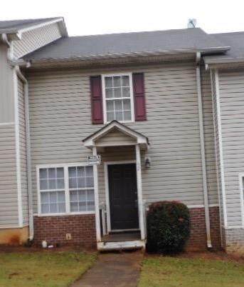 Siding exterior with brick wainscoting, covered entry, and dark roof shingles