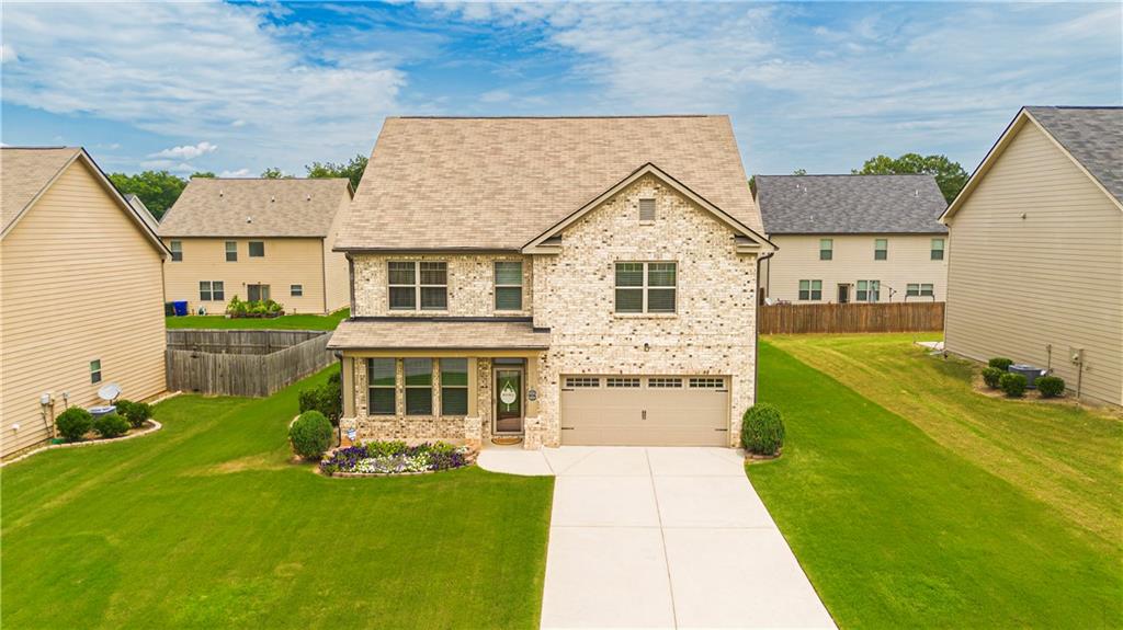 Two-story residence featuring a brick facade, covered porch entry, two-car garage, and a concrete driveway