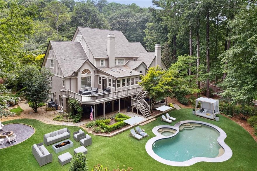 Welcome to expansive luxury living wrapped up in storybook cottage style! Set on a manicured lot on a sought-after cul-de-sac in Sandy Springs, this five-bedroom, four-bathroom home with two half bathrooms and four garage spaces was recently updated and built for enjoying the outdoors with guests. Evoking images of poolside leisure, al fresco dining, s'mores at the fire pit or dinner parties that spill out onto the deck, the picturesque exterior features stacked stone and stucco with a gabled roof and windows. Proceed through the front door to the soaring two-story entrance foyer with limestone floors and a formal staircase to the right that leads to the upper level. To the left, enter the banquet-sized dining room with a chandelier and wainscoting that comfortably seats 12. French doors lead to the completely remodeled chef's kitchen offering new floors/lights/electrical/plumbing, updated wood shelves and cabinets, new quartz countertops and new professional-grade appliances (including a Sub-Zero 48" refrigerator, a 60" six-burner Wolf double range with a double griddle and custom 60" vent hood, a new Cove dishwasher and a new microwave). Surrounded on three sides by peaceful backyard views, the breakfast area features French doors that open to multiple outdoor-deck entertaining spaces. Proceed to the family room with remote Silhouette blinds, a stacked stone fireplace, vaulted ceilings and exposed beams that also offers a rear staircase and a side-door entry to the deck. The cozy fireside living room features built-ins and a coffered ceiling. Hardwood floors flow throughout the main level, which has been updated with a new AC. The main-level primary suite includes a generous spa-inspired bathroom featuring beautiful ceiling detail, a gigantic soaking tub, Carrara marble vanities and floors and a heated marble shower. Upper-level bedroom suites provide generous walk-in closets. The home offers a generous 7,071+/- square feet of space on three levels, plantation shutters throughout and a fully finished terrace level that includes a quartz kitchen, tile and wood floors, a fireplace, a full bathroom, a game area, a fireplace and a media area. Outside, updates include new electrical/plumbing, a new filter unit, a new simmer, new LED pool and spa lights and new Jandy automation. The tile work around the pool has also been upgraded and no-maintenance turf has been added to the backyard.  Several pool photos have been virtually staged. Located in the North Springs High School district, this home is convenient to the Chattahoochee River National Recreation Area.