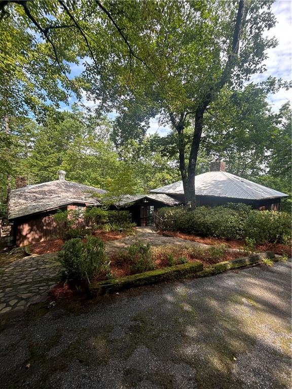 Ideally situated on one of Lake Rabun's largest lots, is this historic lakefront house with big water views and a gradual slope to waters edge. The 5.5+/- wooded acres nestles a unique retreat with unusual privacy on this exceptional point on beautiful Lake Rabun. The charming 1930's cabin with 3 bedrooms, stone fireplace and screened porch has been connected to the 1990's 4 bedroom, 3 bath house. A country kitchen and dining area unite the old with the new. With water views from all sides of the house and privacy, this location on a point provides outstanding advantages. The main level of the modern side of the house boasts an inviting, light filled Living room with fireplace, a primary suite with bath, and a large guest suite with bath. The bright terrace level hosts a large entertaining room with fireplace and two guest rooms with shared bath. A patio off this room expands the entertaining area and offers access to the pathways that lead to the two boathouses and two sandy beaches on either side of the point. The two story, two stall boathouse was constructed to accommodate more modern watercraft while the one story boathouse is home to the antique wooden boat and fishing boat. Enjoy swimming in the two coves that flank this special point or use the sandy beaches on each side. A stone lake wall protects approximately 600 ft of shoreline. The property has a septic permit from the Rabun County Health Dept. for 7 bedrooms which is a rarity on the lake. Make this your second home or primary residence; remodel, renovate or build your dream home on this extraordinary property. Just 20 minutes to Clayton, 10 minutes to Lakemont Village, take the boat to Hall's Boathouse and the Lake Rabun Hotel in just 5 minutes. Convenient access with paved roads and paved driveway to the doorstep. This is a GA Power lease lot and requires a transfer fee.