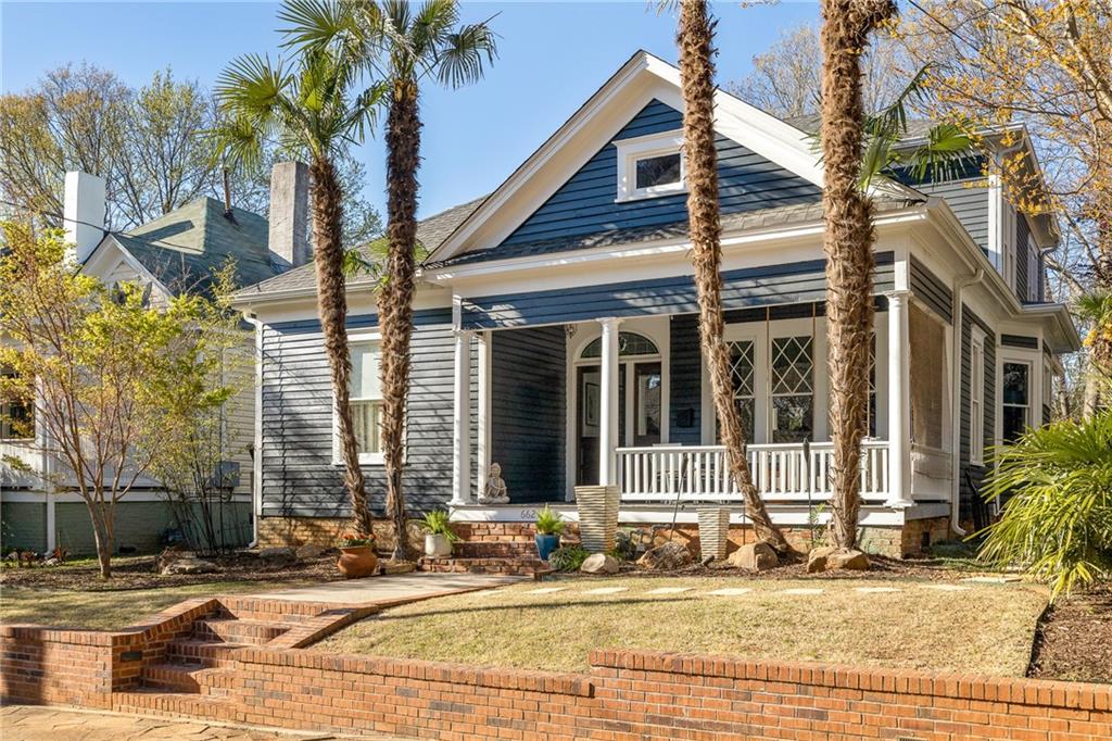 Welcome to 662 Rosalia, a beautifully re-imagined Victorian bungalow situated on one of the most beloved blocks in the heart of Atlanta's historic Grant Park district. As soon as you arrive, you'll be transported to a tropical oasis by the four towering windmill palms that welcome you to the property. Standing tall against the backdrop of the house's luxurious black exterior, these cold-hardy palms have been welcoming friends and guests for the past 18 years since they were first planted by the homeowners. As you step onto the front porch, the original diamond-patterned, 12-over-1 divided light windows, palladium transom, and tongue-and-groove porch floors catch your eye. But the real magic begins as you open the front door to a spacious living room with a grand central hallway, separating the living spaces from the downstairs bedrooms. The wide-plank solid hardwoods float beneath your feet as you explore the room. You'll also notice the original fireplaces with historic mantels and their original majolica tile in the living room and dining room. Don't miss the dining room's original stained glass buffet transom window. The primary bedroom boasts a luxurious atmosphere with recently installed wrap-around wallpaper, designer lighting, and custom drapery reminiscent of a South Beach resort. The recently renovated primary bathroom exudes sleek and sophisticated vibes and leads into a custom walk-in closet with ample storage space. On the main floor, a guest suite with similar features and a guest bathroom with convenient washer-dryer hookups await. A back door leads to the lush backyard area and a detached office space. As you ascend the stairs, you'll be greeted by a sprawling media/family area. At the end of the hallway, the accordioned French doors open up to a tranquil screened porch overlooking the lush backyard and even offering a glimpse of the downtown skyline in winter. Upstairs, you'll find two sizable secondary bedrooms, a hallway bathroom with dual vanity perfect for the kids, a convenient office space, and an oversized laundry room. The backyard is the epitome of a tropical oasis, complete with a patio kitchenette featuring a raised fire pit and stainless steel grill. The soothing sounds of waterfalls and streams flowing under boardwalk bridges add to the ambiance, while a crystal clear koi pond provides a peaceful spot for relaxation. An offset detached 1-car garage, transformed into an office space resembling a rainforest treehouse, is positioned at an angle from an open alley. The abundant variety of semi-tropical plants and palm trees contribute to the feeling of being transported to a luxurious Costa Rican retreat.
