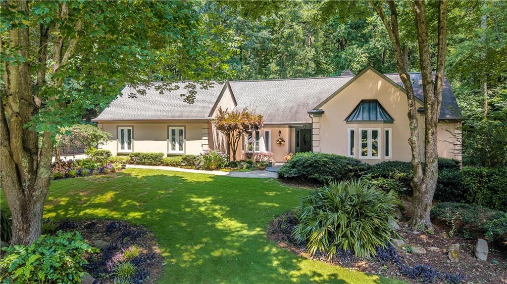 Imagine living in your own private park with a gentle stream and a waterfall behind. Enter the foyer and open stairway. To your right is the primary bedroom suite with a tall vaulted ceiling, bay windows, and enough room for a private sitting area. It features a large walk-in closet and an ensuite bath.
Behind the stairway in the hall is a wet bar with easy access to the great room. Down the hall is another bedroom with a vista to the deck and yard at the back. The walk-in closet and adjacent bath make this home unusual with two bedrooms on the main floor.
Wait until you see the great room! It boasts a soaring cathedral ceiling with decorative beams, tall windows, and a fireplace. There is easy access to the backyard and deck. The great room is open to the kitchen, which has a very large dining room with a bay window and open access to the great room and kitchen.
The kitchen features a wonderful new cooktop with a counter making food prep easy. A new microwave and multi-function oven will help you with all your cooking needs. Generous counter and cabinet spaces, as well as an eat-in dining area, all open to the great room. There is access to the covered porch, patio, and outdoor kitchen.
In the hall, the laundry room is to the right and a huge pantry to the left with access to the garage. In the garage, there is a half bath and a workroom.
Upstairs, you will find two bedrooms and a bath separated by a balcony overlooking the great room with a perfect view of the artistic beams.
Outside, the entertaining areas are an absolute delight. The creek which runs through the yard provides the gentle music of a babbling brook. Backyard is fenced.
Don’t miss this home in a neighborhood with a variety of homes and prices, with the top at over two million.