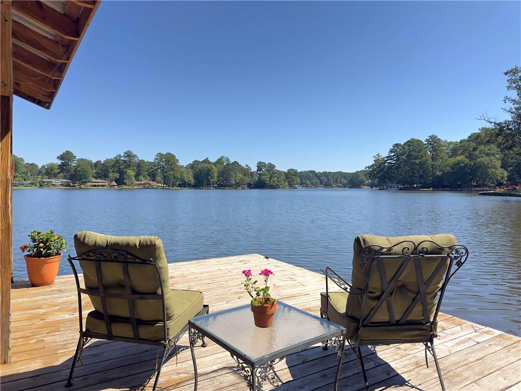 This stunning waterfront home on beautiful Lake Jodeco sits on an expansive private lot with access to deep water and stunning views. As you step into this beautifully updated brick home, you are greeted with a breathtaking panoramic lake view from the entire back of the house. The open floor plan makes it ideal for entertaining, offering plenty of living space. Every room features special touches-from the oversized living room that opens onto the expansive back deck, which runs the full length of the house, to the open kitchen overlooking the lake with ample cabinet space and granite countertops, a tasteful updated laundry room, and the large office/second family room with a private deck and access to the main deck. The master suite features a beautiful custom walk-in closet and ensuite bath, and the main floor boasts gorgeous hardwood floors. Downstairs, you'll find a workout room, game room, built-in bar, additional storage, and a workshop. The backyard is breathtaking, with a well-manicured zoysia lawn, 108 feet of prime fishing water, and lake views. A newly built dock features a covered boat slip and an additional covered and open area for relaxation and entertaining while enjoying the sunsets. To the side of the property, there's a paved path and private boat ramp, along with an additional storage shed perfect for lawn equipment or the highly sought-after She Shed. Lake Jodeco provides 85 acres for you and your family to enjoy boating, swimming, and fishing for trophy bass and crappie. Whether you're enjoying retirement or raising a family, this lake property is perfect for you. Lake Jodeco is a private lake just south of Atlanta, only 13 miles from Atlanta Hartsfield-Jackson and 18 miles from Downtown Atlanta. Additional upgrades include a new roof in 2025, new HVAC in 2024, new carpet installed downstairs in 2025, a new back deck, a 4-year-old dock, a poured cement lake wall, an in-ground irrigation system with a new pump (no extra cost to water the lawn), and a fenced backyard. Welcome home to your private oasis!