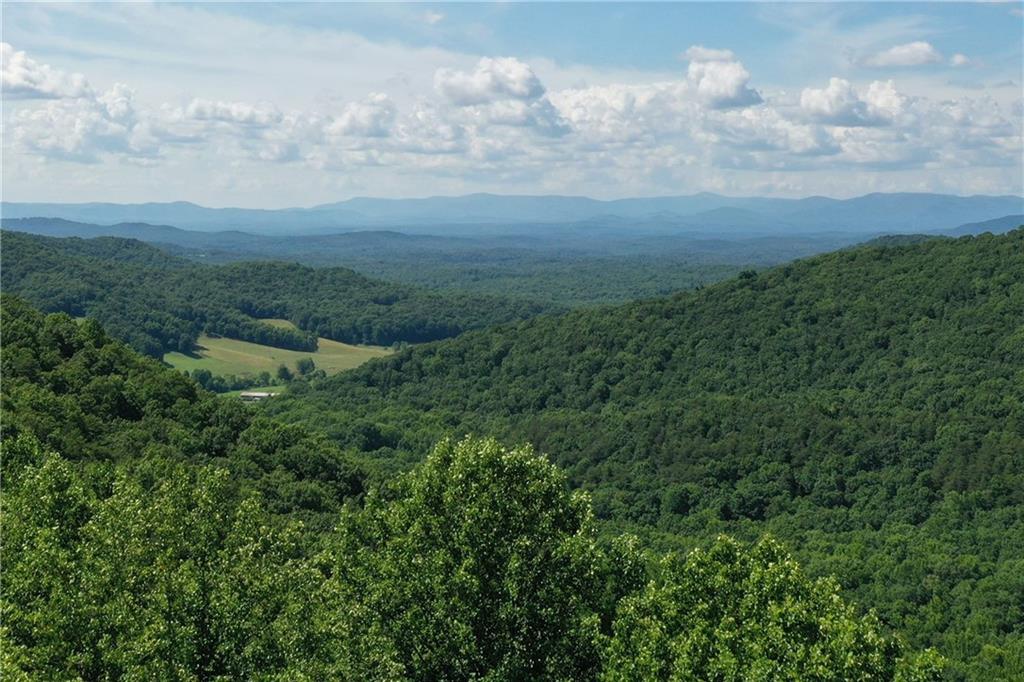 Long Range Seasonal Mountain views with nice homesite area on 3.67 acres! Seasonal views in the Summer where you'll see a peek; when the leaves fall off, your views open up to an AMAZING vista of both long range mountain and valley views. The shape of this upsloping lot really opens you up to multiple building orientations and views. The left side of the lot has a really nice building site and has such an easy driveway towards the left border. Consisting of 2 combined lots, the right side of the combined lot gives you so much privacy! It also has a small SPRING head on the right side of the original lot (now considered the middle of the lot) so you'll hear the sounds of water as it gently trickles down the mountain side. This double-lot has been surveyed and combined creating 3.67 acres. Underground electric, phone, cable, and fiber internet. Easy to get to navigate, the subdivision of Falling Waters, is a gated mountain community offering a fishing lake, hiking, and lots serenity. The terrain photos are approximation only by using GPS to help gain a rough idea of the lay of the land. Home design and vista pruning must be approved by HOA Architectural committee. Custom home w 2 car side entry garage and paved drive, 2000 sqft min preferred. Soil test on file in Gilmer County.