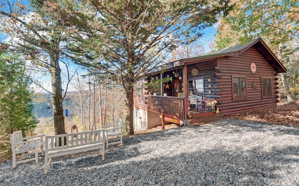 Welcome to your private mountain hideaway, tucked into the serene landscape of Yahoola Valley just 15 minutes from downtown Dahlonega. This charming log cabin, nestled on a full acre that borders the National Forest, offers an exceptional blend of seclusion and natural beauty. Inside, you’ll find a warm and inviting layout with two bedrooms and one full bath, making it perfect for a small family, weekend retreat, or peaceful full-time residence. The eat-in kitchen is a cozy spot for meals, offering a front-row seat to the mountain views just outside the window. Built in 1999, the home maintains its rustic charm while providing the durability of a metal roof. The real showstopper, however, is the outdoors. THIS VIEW!!!! Wake up to sweeping mountain views, enjoy the peaceful forest as your backyard, and at night, marvel as the twinkling lights of Dahlonega glow in the distance. Whether you are sipping coffee on the porch or heading out for a hike right from your property line, this cabin offers the ultimate North Georgia mountain retreat.